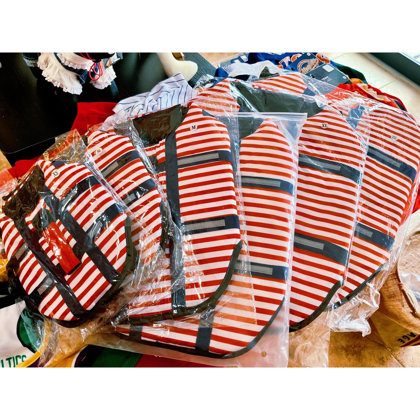 Red and white striped bags with black handles, stacked and wrapped in plastic.