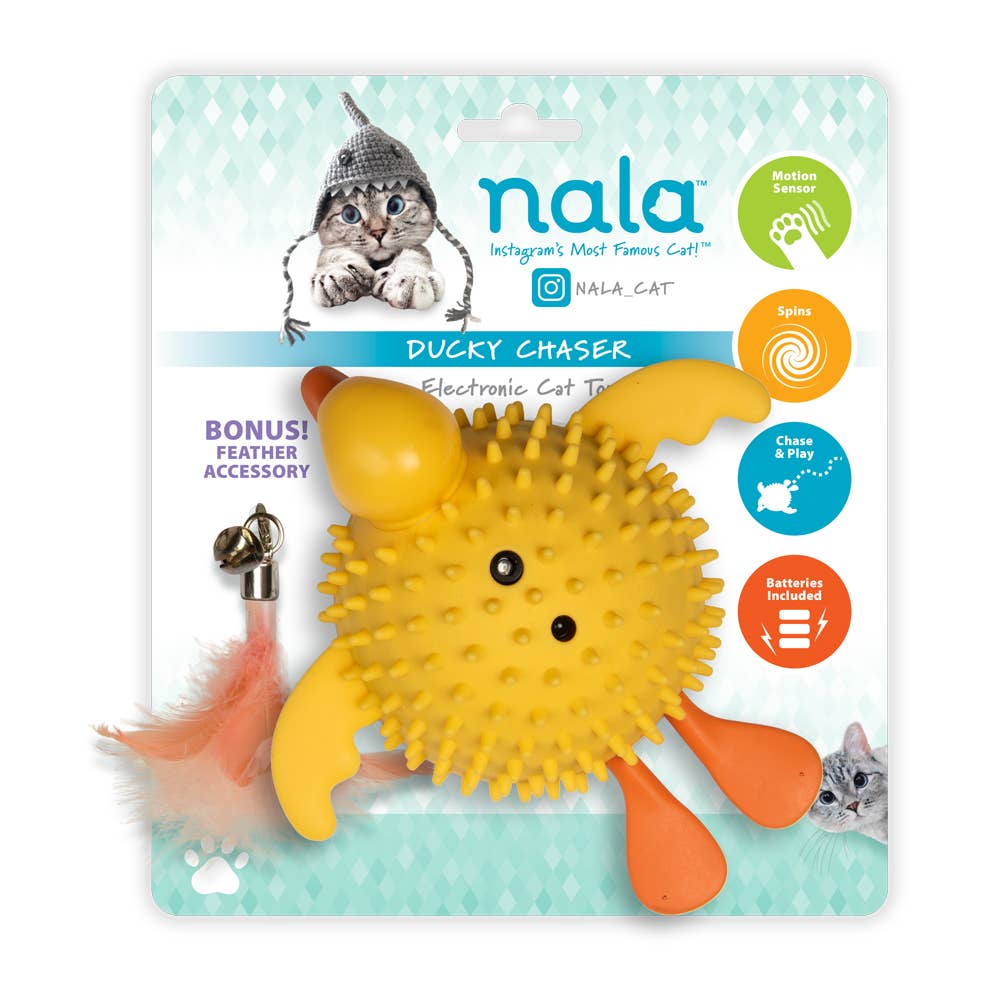 Yellow spiky duck toy with orange feet, feather accessory, and packaging featuring a cat.
