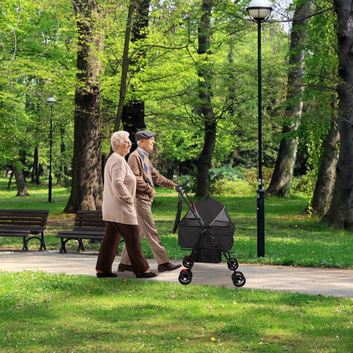 Elderly couple walking with a stroller on a park path, surrounded by green trees and benches.