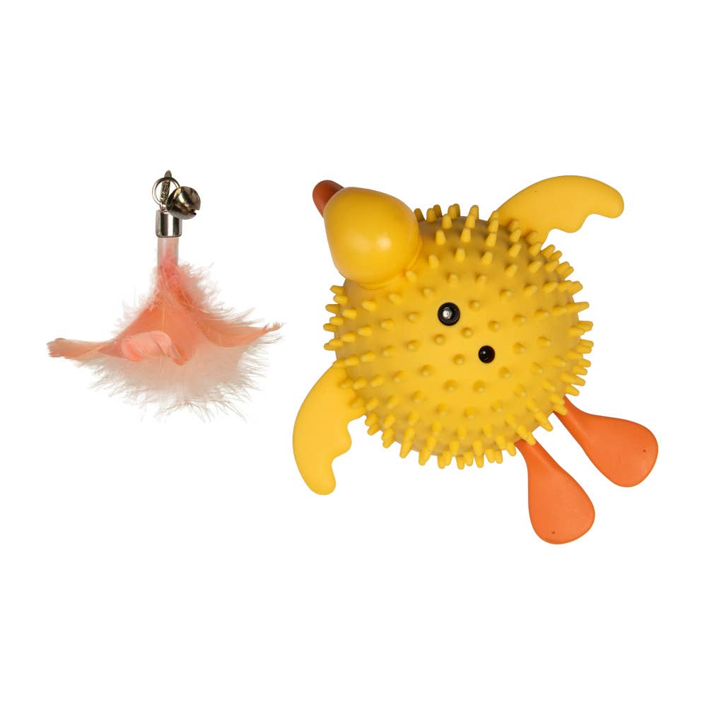 Yellow spiky rubber duck toy with orange feet and a pink feather with a bell.