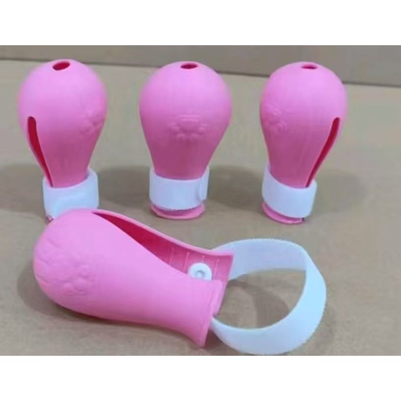 Four pink rubber bulb syringes with white straps on a beige surface.