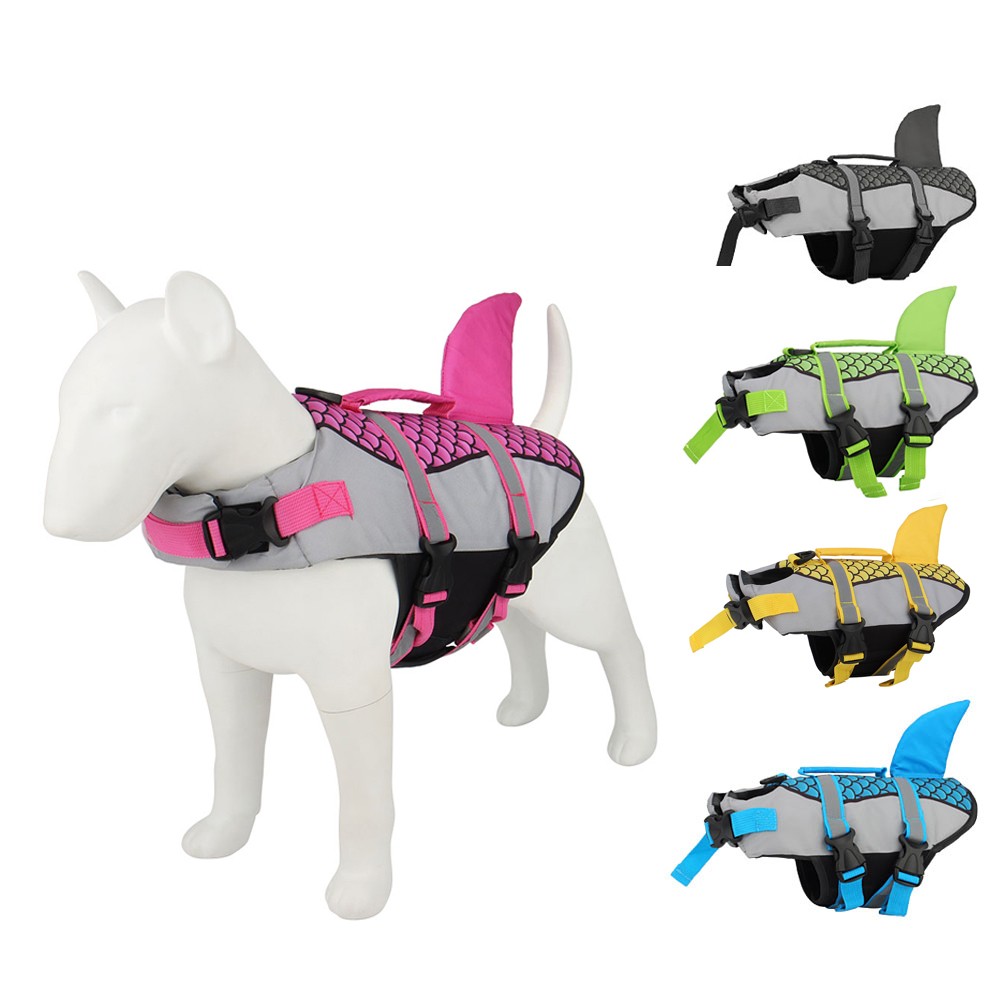 White dog mannequin wearing a pink shark fin life jacket; four color options shown: gray, green, yellow, blue.