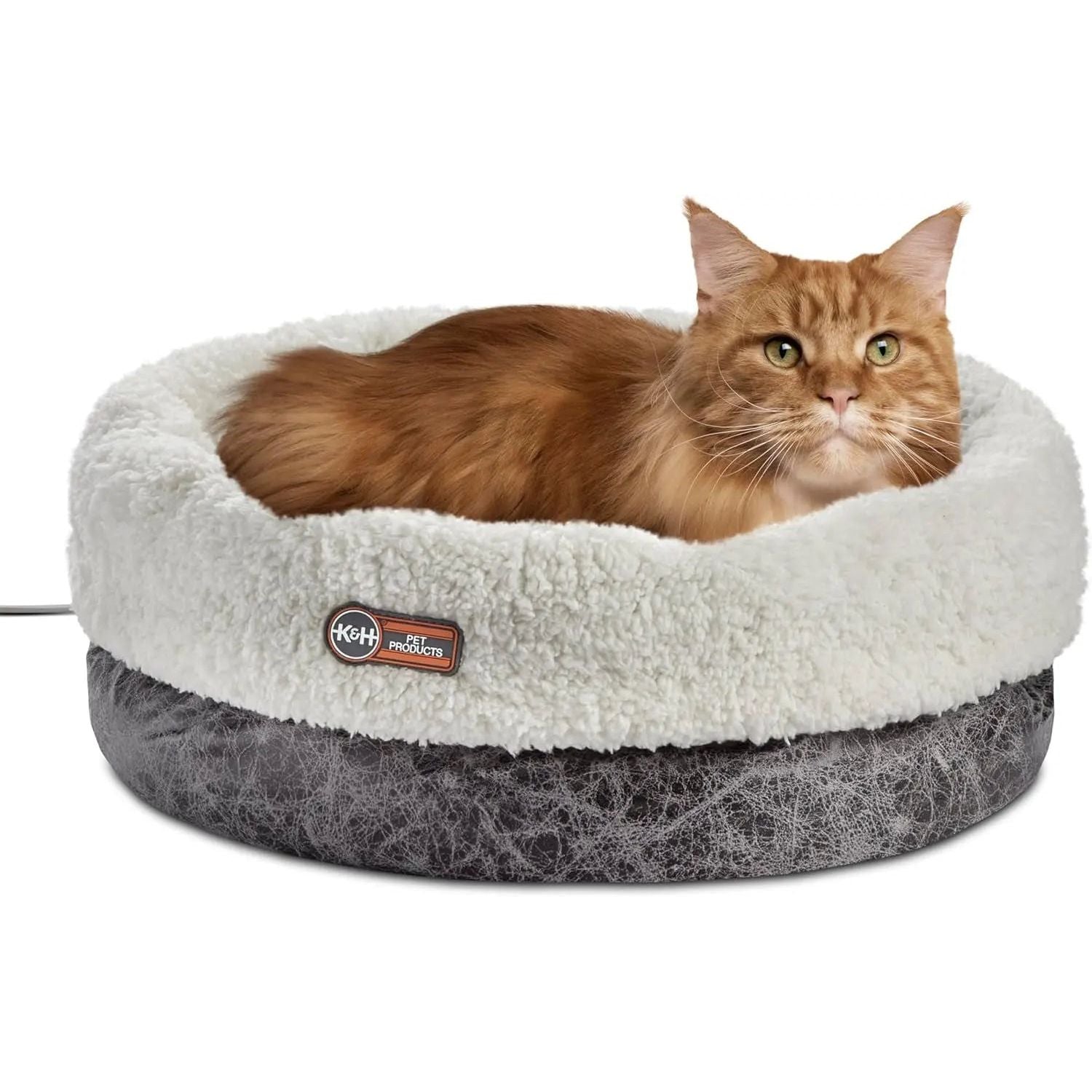 Orange cat in a fluffy white and gray pet bed with a K&H Pet Products label.