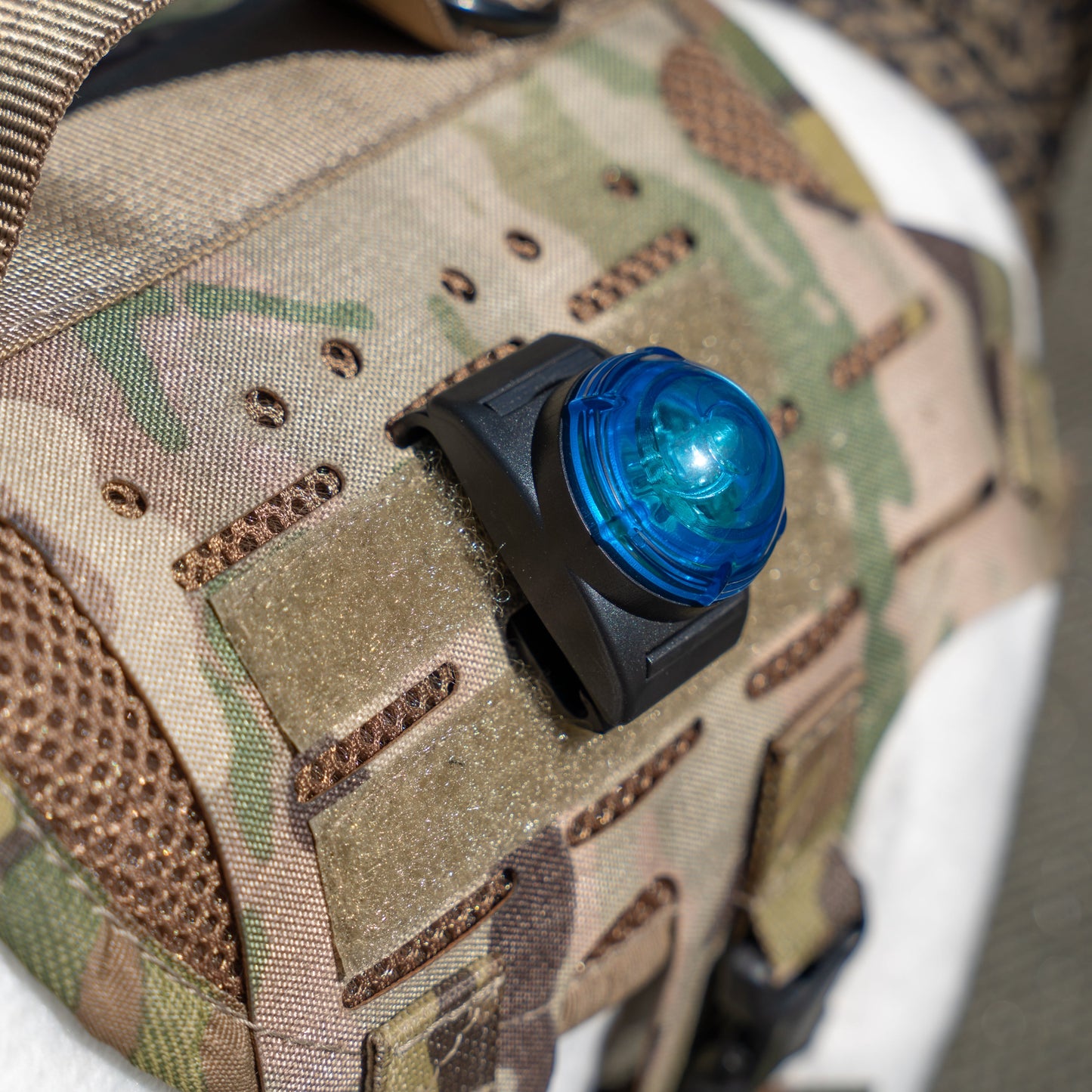 Camouflage fabric with a blue light attached, featuring Velcro straps and mesh details.
